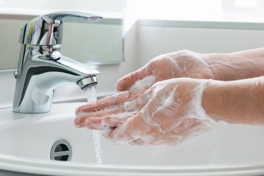 Hands washing with soap under running water.