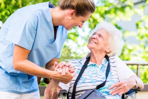 Nurse assisting elderly woman in wheelchair.