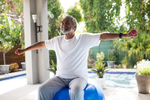 Elderly man exercising on a yoga ball.
