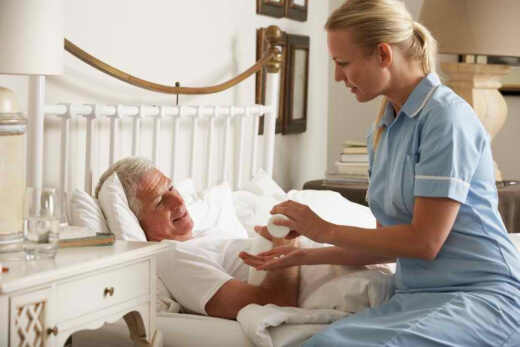 Nurse assisting elderly man in bed.