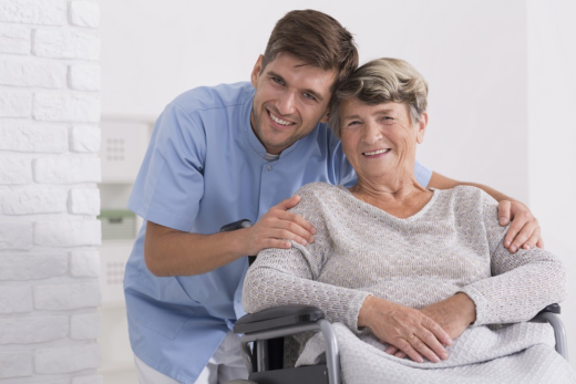Caregiver smiling with elderly woman in wheelchair.