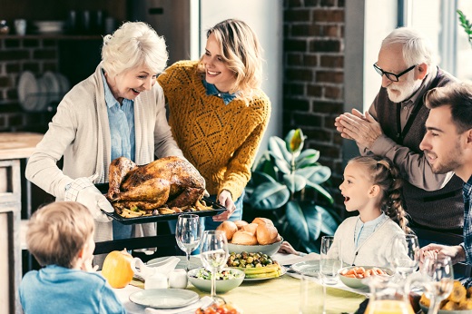 Family gathered around table with Thanksgiving turkey.