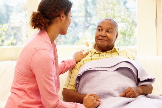 Caregiver comforting elderly person with blanket.