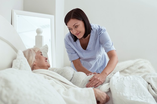 Nurse caring for elderly woman in bed.