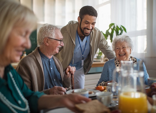 Elderly people and caregiver enjoying breakfast together.