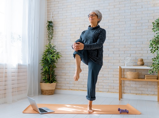 Elderly woman practicing yoga at home.