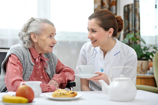 Elderly woman and caregiver sharing tea.