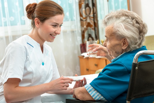 Nurse assisting elderly woman with medication.