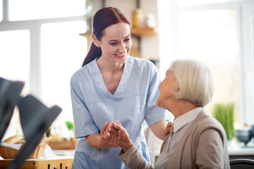 Nurse smiling and assisting elderly woman.