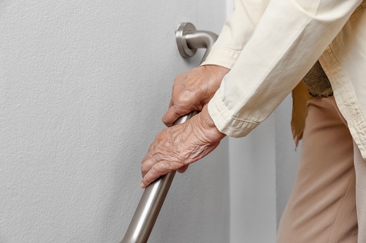 Elderly person holding a handrail for support.
