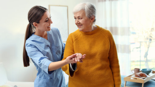 Caregiver assisting elderly woman at home.