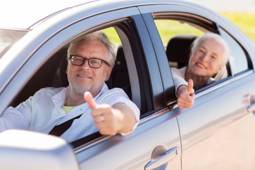 Older couple in car giving thumbs up.
