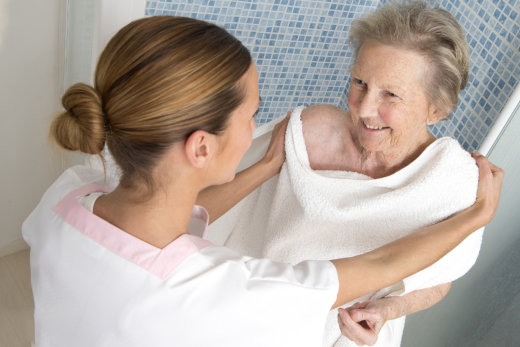 Caregiver assisting elderly woman with towel.