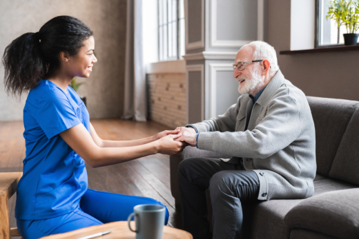 Nurse comforting elderly man on couch.